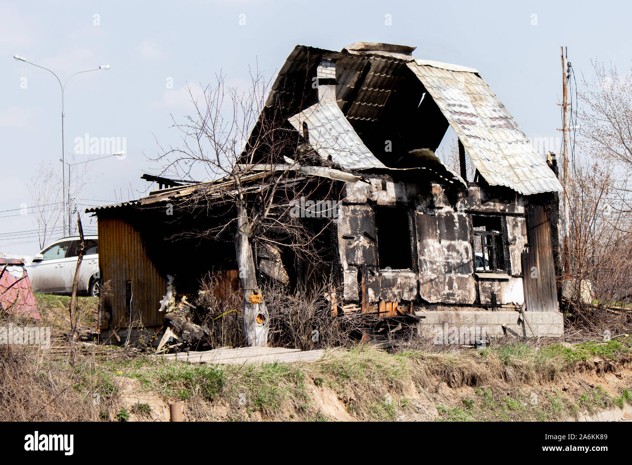 Der ausgebrannte Country House ist eine Etage, eine einsame verkohlten Gebäude. Brandstiftung Cottage, schwarz Windows, gebrochene, verbrannte Frucht Baum Stockfoto