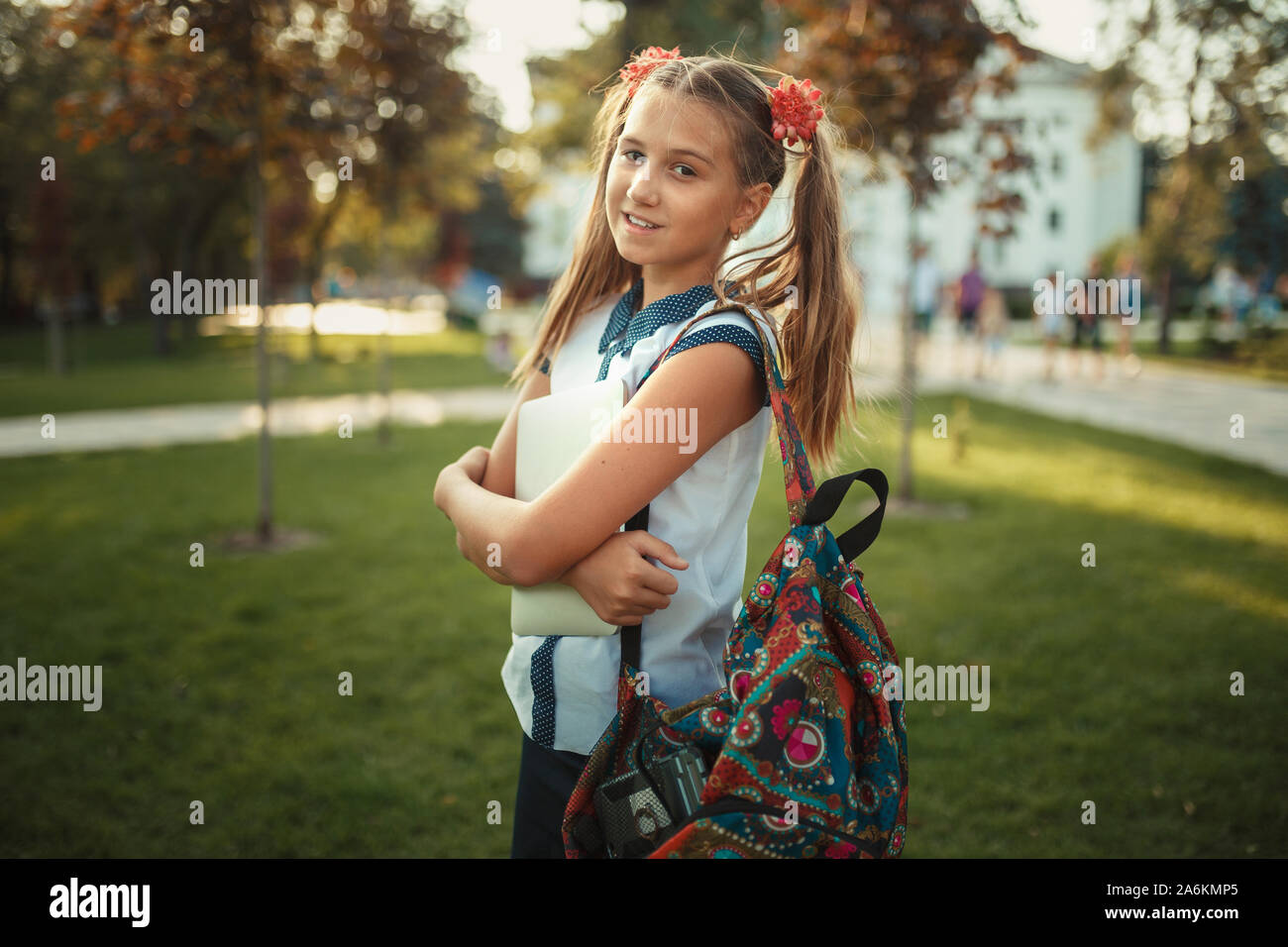 Ein schönes Mädchen im Schulalter steht ein Baum und Halten einer Tablette. Schulmädchen trägt einen Rock und ein T-Shirt mit Schuhen Stockfoto