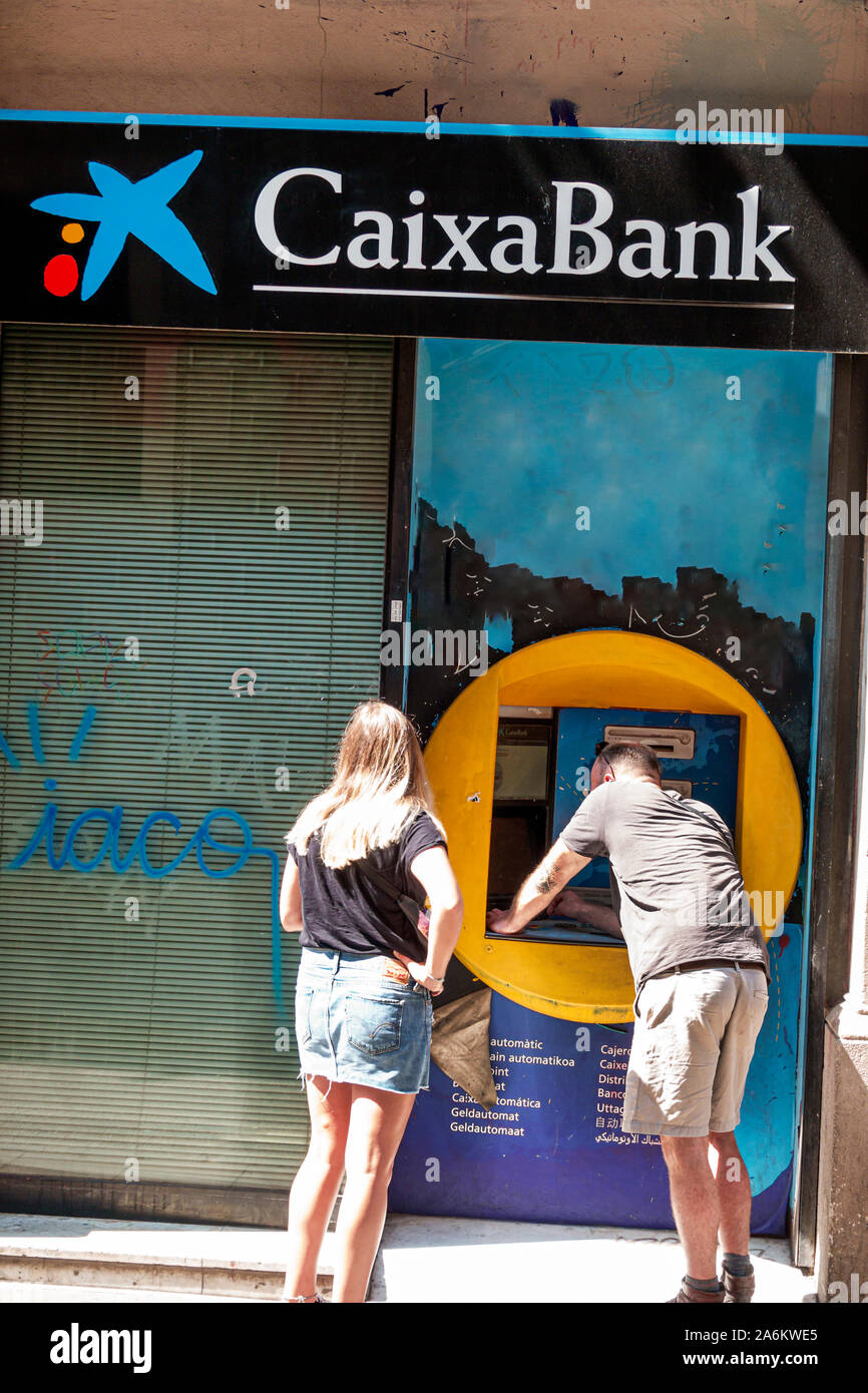 Barcelona Spanien, Katalonien Ciutat Vella, El Raval, Carrer dels Angels, Caixa Bank, Geldautomat, Geldautomat, Mann, Frau, Transaktionen durchführen, Graffiti, ES1908 Stockfoto