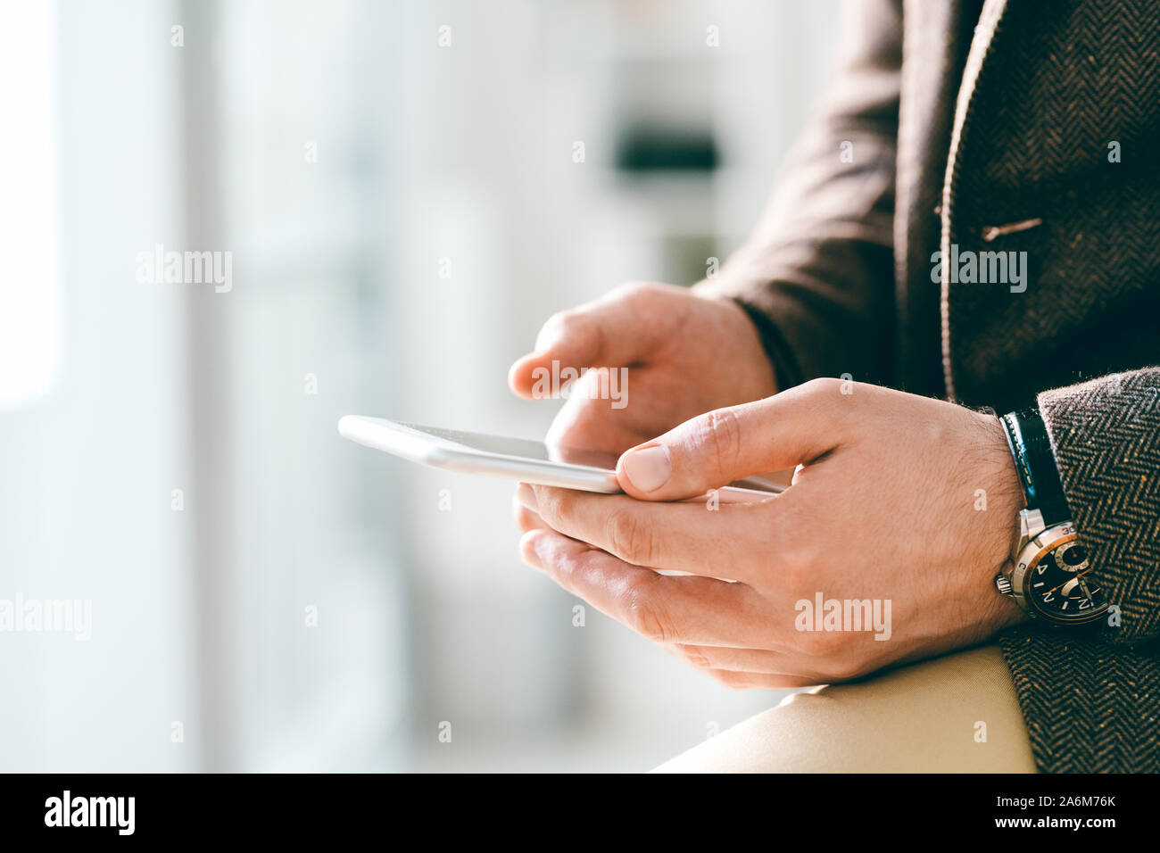 Junge elegante Geschäftsmann mit Armbanduhr holding Smartphone während texting Stockfoto