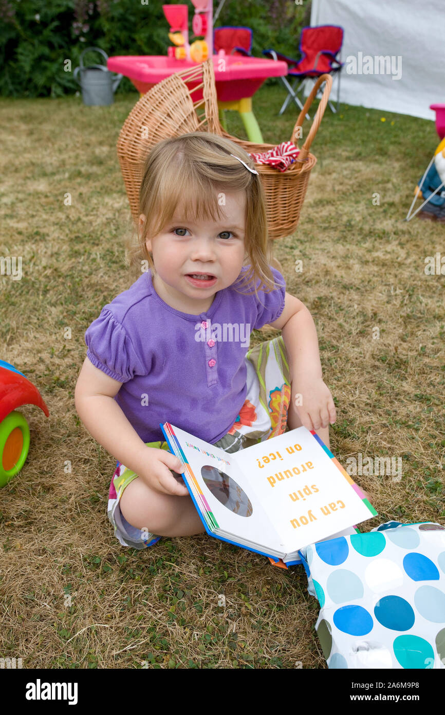 Zwei Jahre altes Mädchen saß auf dem Boden an ihrem neuen Buch suchen Stockfoto