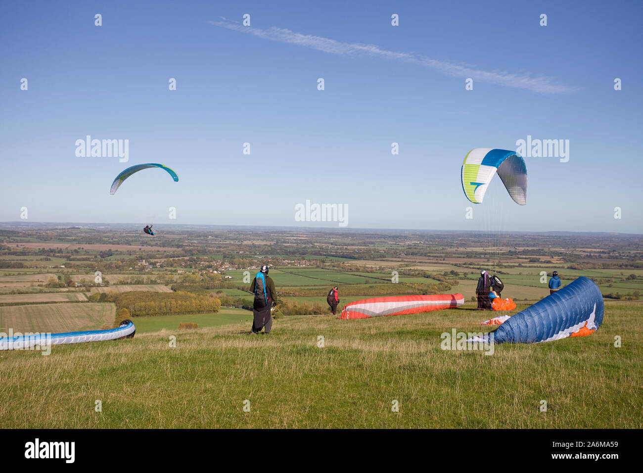 Gleitschirme, die von den Hügeln von Uffington White Horse Hill in Oxfordshire, England Stockfoto