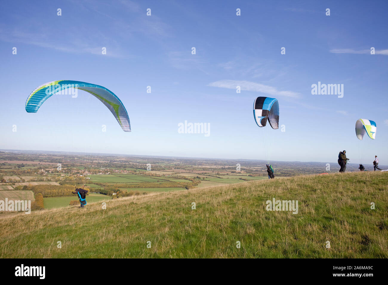 Gleitschirme, die von der Oberseite des Uffington White Horse Hill in Oxfordshire, England Stockfoto