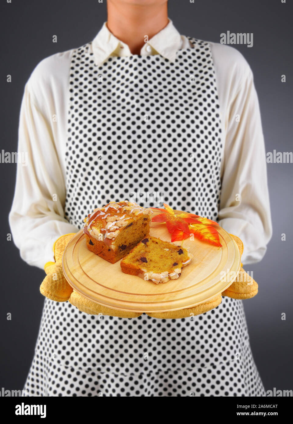 Nahaufnahme einer Hausfrau in einer Schürze und Ofenhandschuhe holding Holz Servierplatte mit silced Kürbis Brot Stockfoto