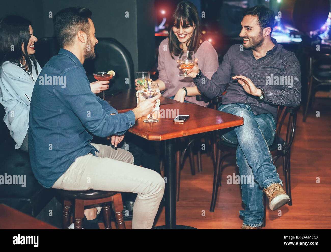 Gerne Freunde trinken Cocktails innerhalb jazz Cocktail Bar - Tausendjährigen junge Leute Spaß haben und gemeinsam in britischen Pub lachen Stockfoto