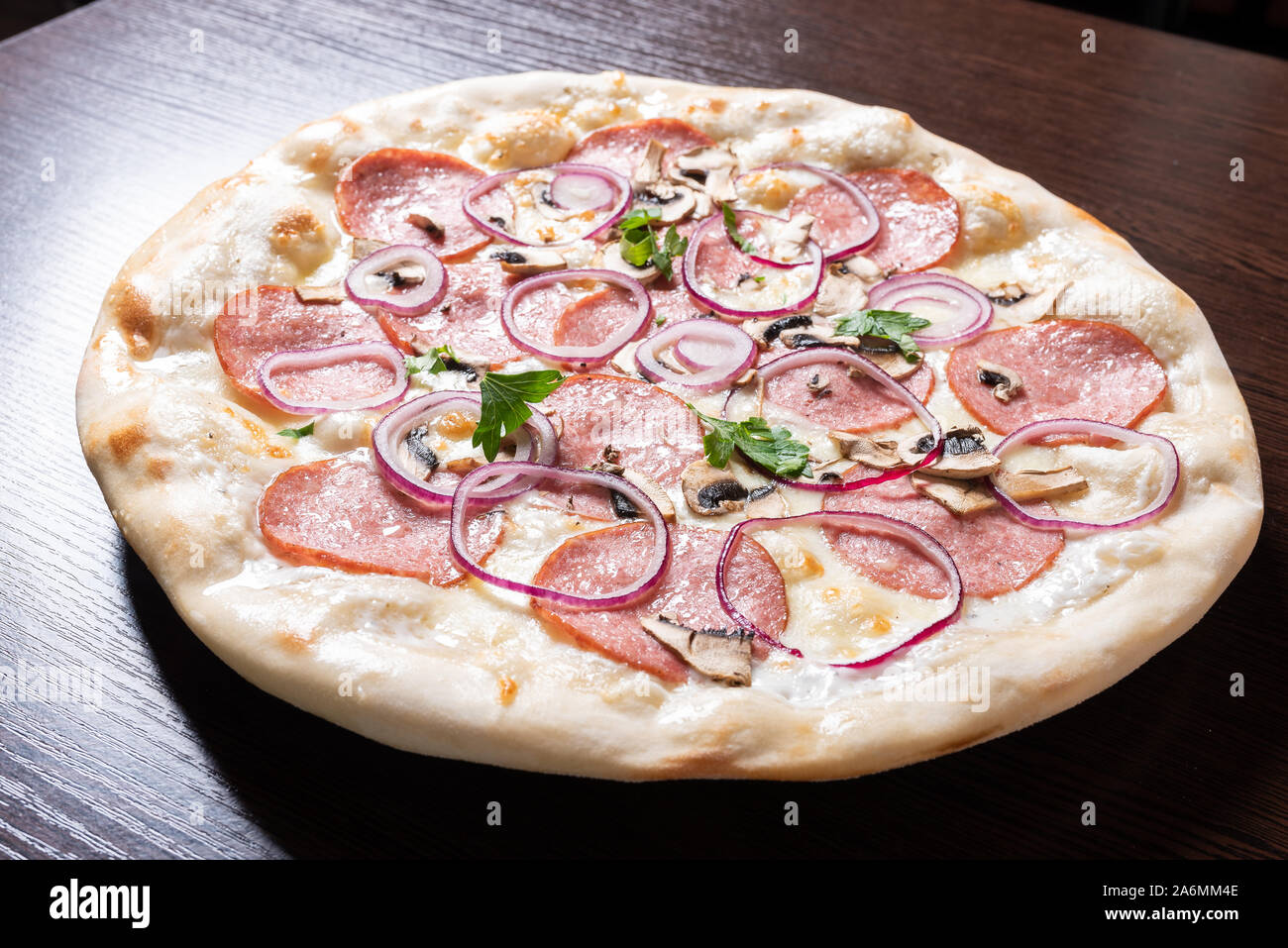 Billige Pizza mit Salami, Zwiebeln und Pilze. Stockfoto