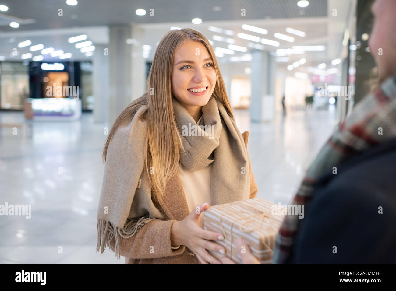 Junge lächelnde Frau, die ihren Mann unter Geschenkset Stockfoto