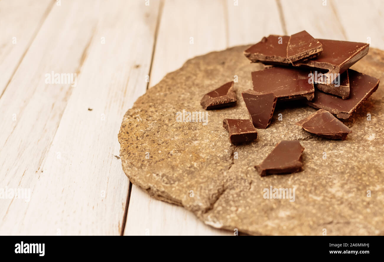 Dunkle Schokolade ohne Zucker und Glutenfrei, für Diabetiker und Allergiker. Stücke Schokolade liegen auf einem Stein Board auf eine Tabelle in einem rustikalen Stil. Kopieren Stockfoto