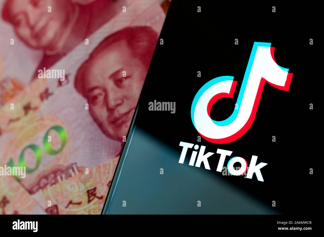 TikTok app Logo auf dem Bildschirm des Smartphones und verschwommenes Chinesische Geld hinter. Stockfoto