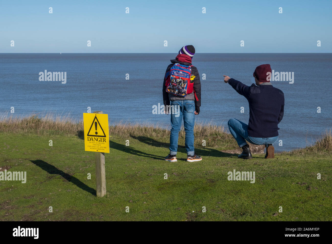 Zwei Besucher des dunwich Klippen, Dunwich, Suffolk, ignorieren die Gefahr Warnzeichen. Stockfoto