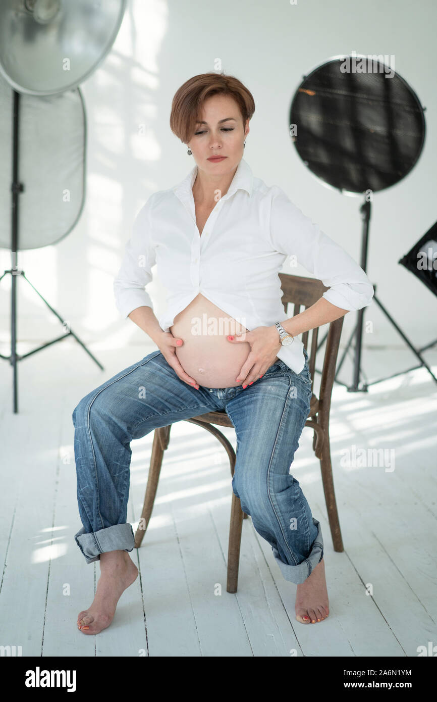 Schwangere Frau posiert an der Kamera In Photo Studio In der Mitte von Foto-Geräte. Schönheit Schwangerschaft Konzept. Stockfoto