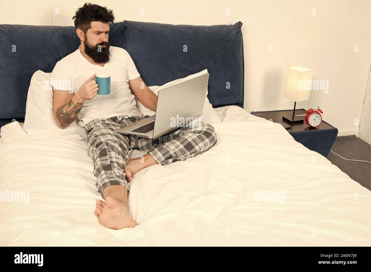 Schnell am Morgen unterhalten. Eine Pause. Zu viel Arbeit. All seine Energie zu arbeiten. Geschäftsmann mit Computer. bärtiger Mann Arbeiten am Laptop. Mann im Schlafzimmer Kaffee trinken. Energie und Müdigkeit. Stockfoto