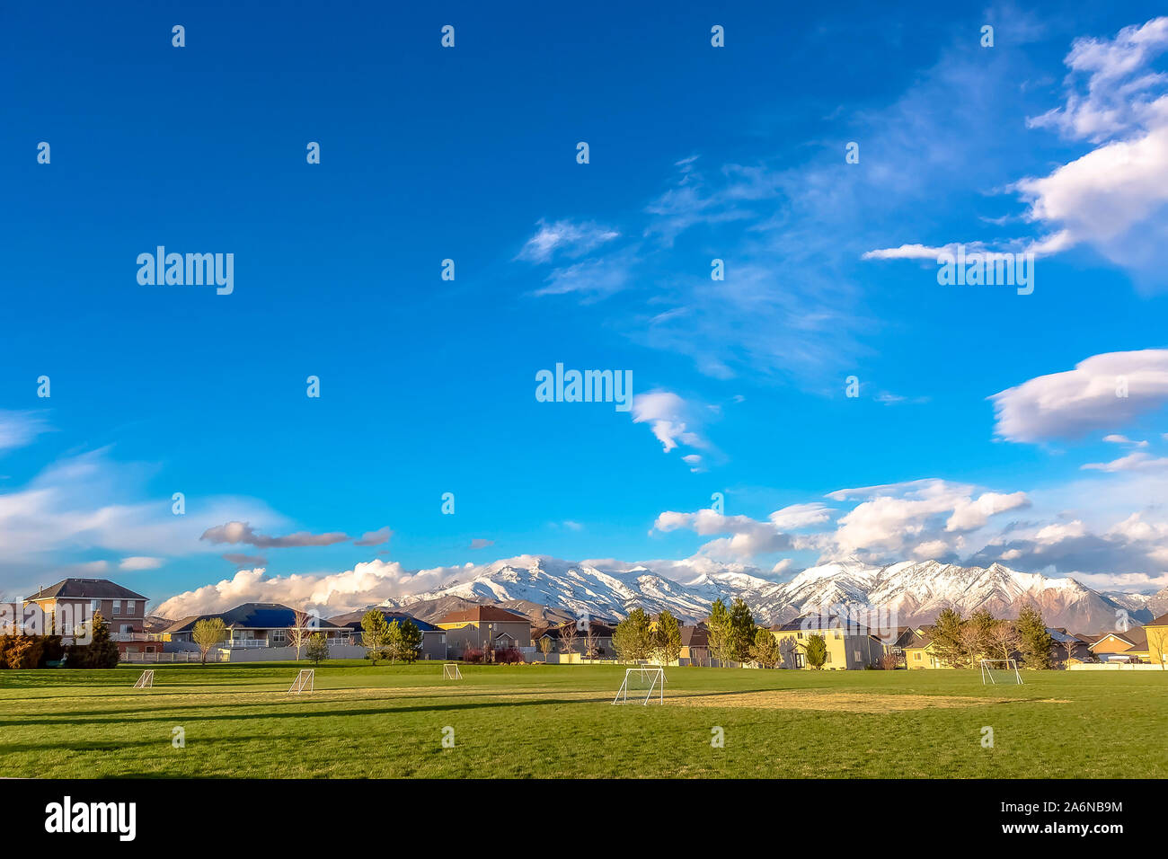 Grüne Sportplätze mit schneebedeckten Berge im Hintergrund Stockfoto