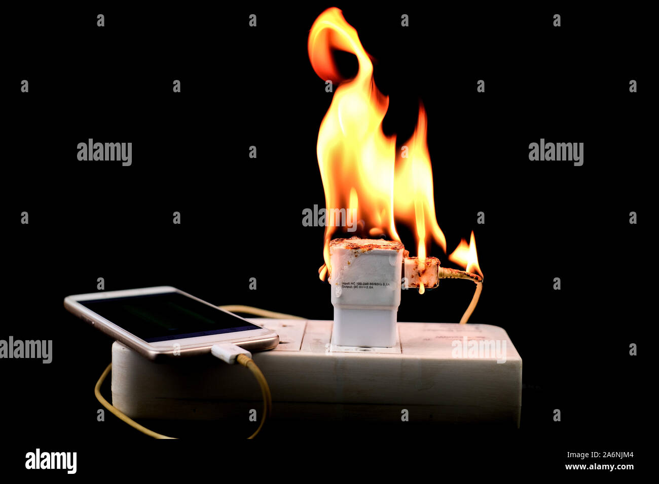 Auf Feuer Adapter Smart Phone Charger an Stecker in Steckdose auf schwarzem Hintergrund Stockfoto