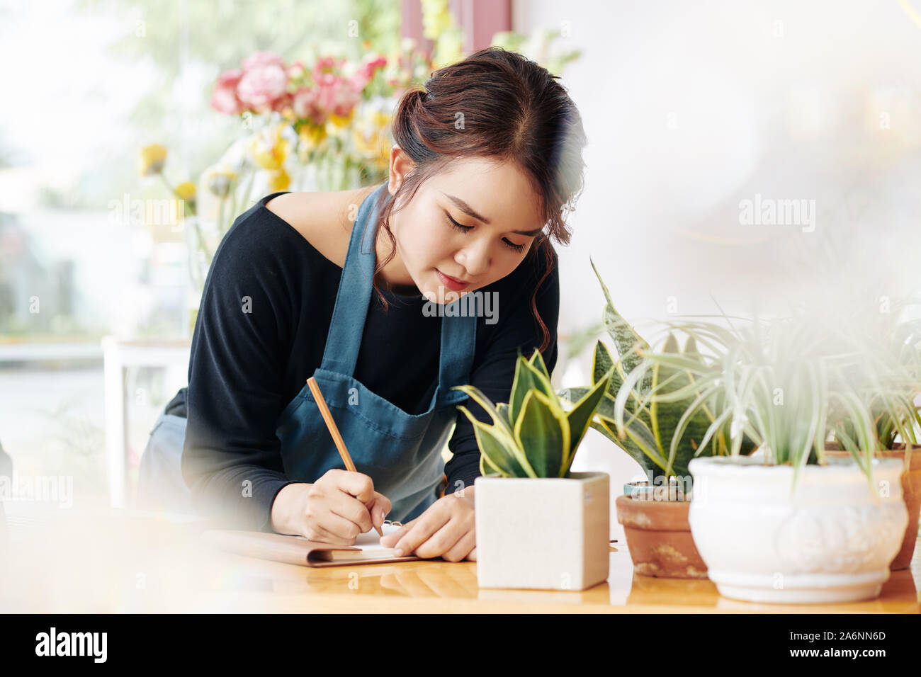 Jungen Asiatischen florist Schreiben Liste der Dinge, die sie braucht, um heute zu tun Stockfoto