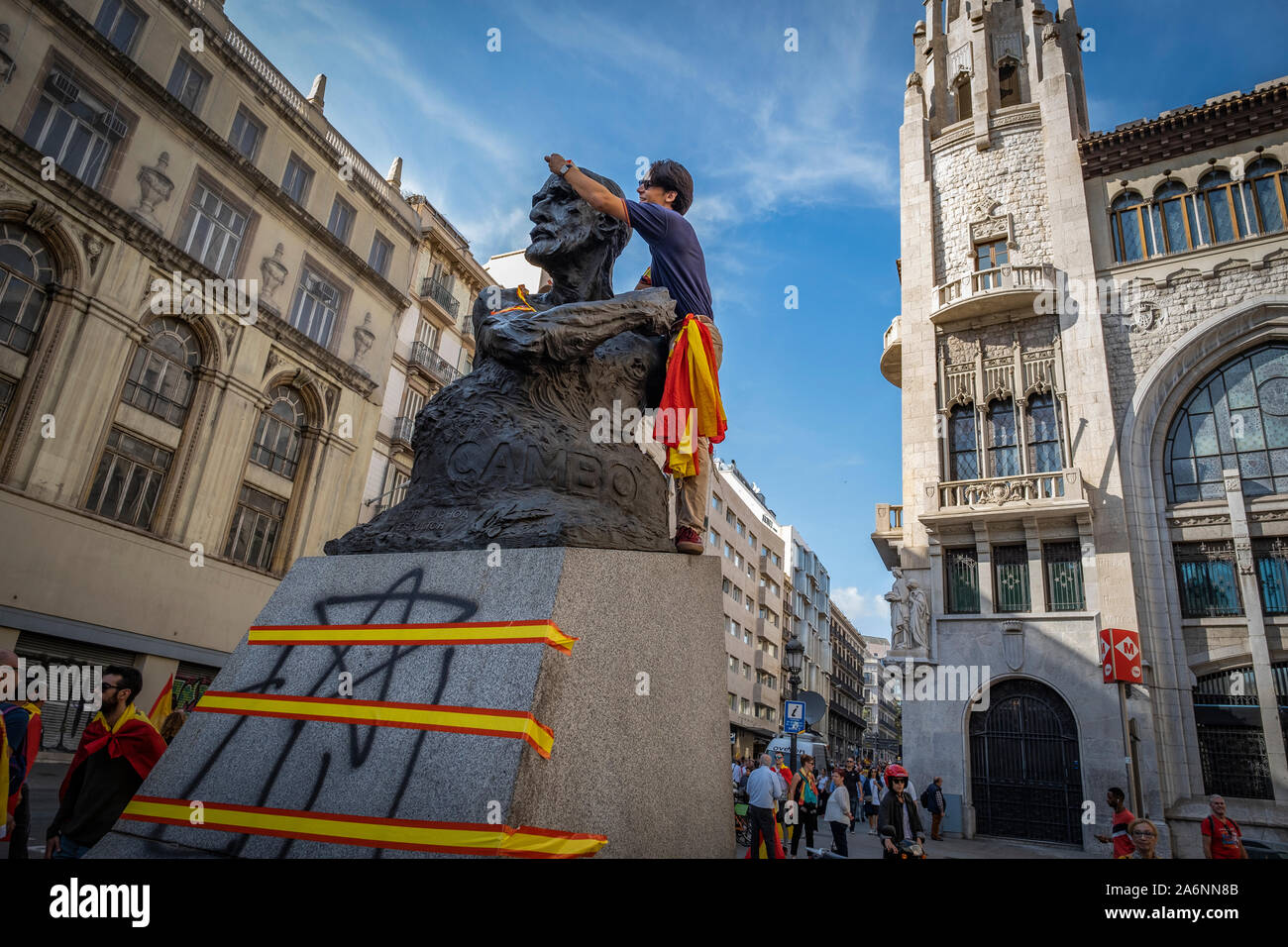 Barcelona, Spanien. 27 Okt, 2019. Eine Demonstrantin auf die Skulptur der ehemalige Politiker und katalanische Geschäftsmann, Francisco Cambó anspannen Klebestreifen mit der spanischen Flagge während der Demonstration. Große konstitutionelle Mobilisierung in Barcelona. Laut Quellen aus der Städtischen Guard, die Demonstration hat zusammen 80.000 Menschen, die unter dem Motto gezeigt haben: Für Concord, für Katalonien, genug! Credit: SOPA Images Limited/Alamy leben Nachrichten Stockfoto
