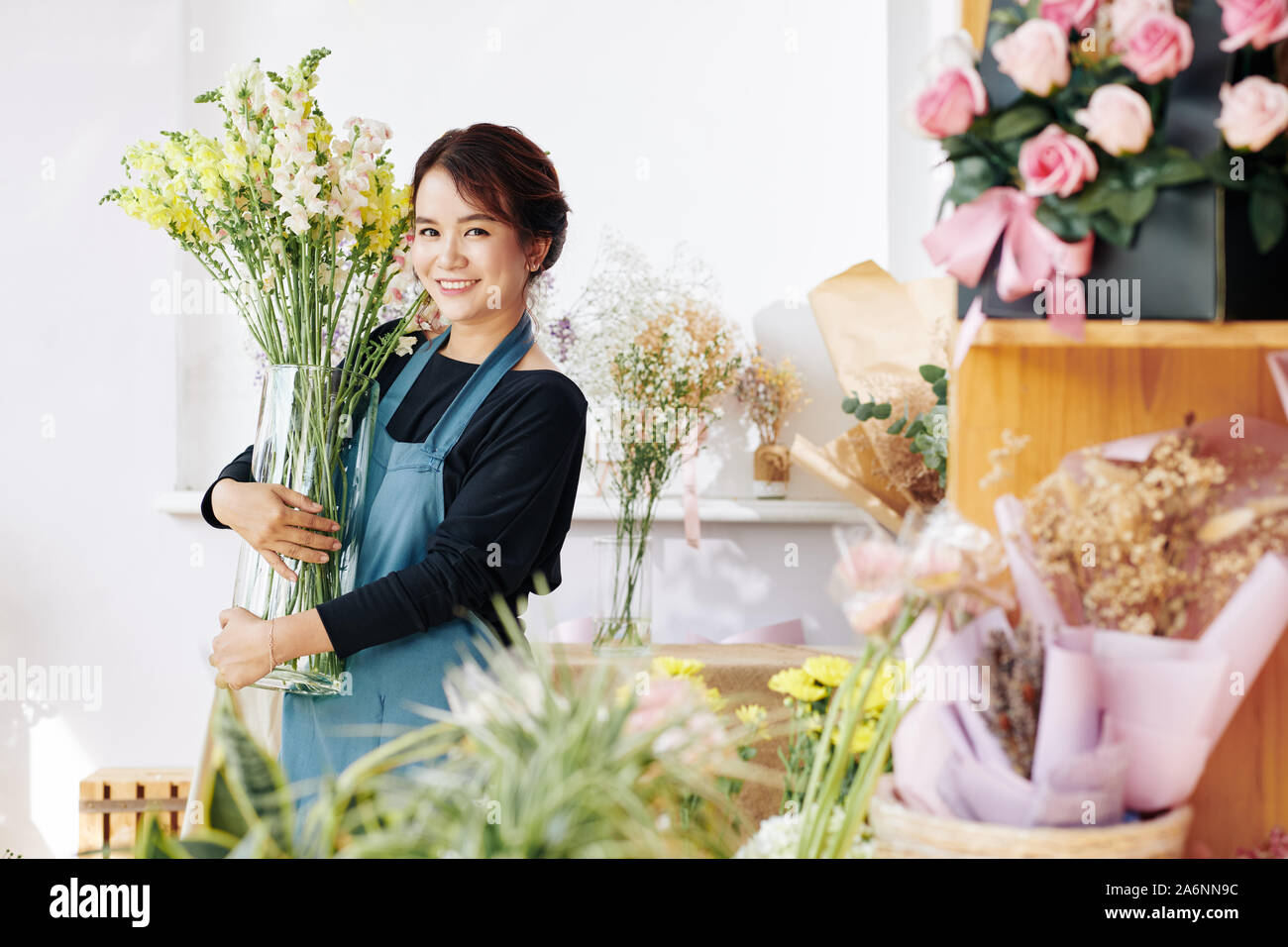 Glückliche junge Flower Shop Eigentümer entfernen große Vase mit frischen Blumen Stockfoto
