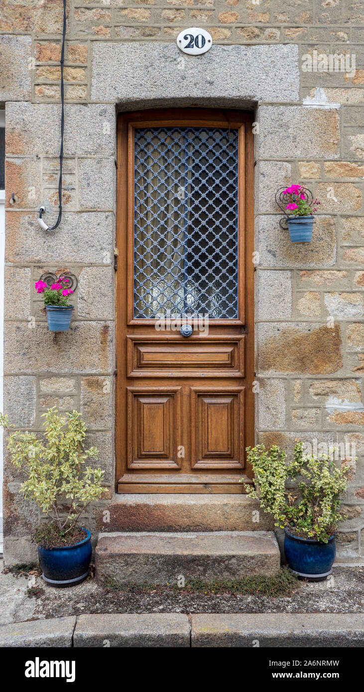 Tür Nr. 20, typische Post World War 2 Normandie Tür, geschnitztem Holz, Gusseisen Fenster Schutz, Blumen und Pflanzen neben Stockfoto
