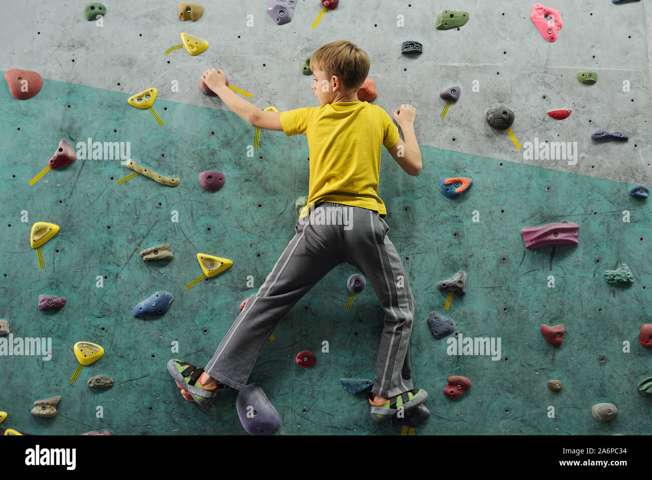 Rückseitige Ansicht des aktiven Schüler in Sportkleidung verschieben Nach oben Entlang Kletterwand Stockfoto