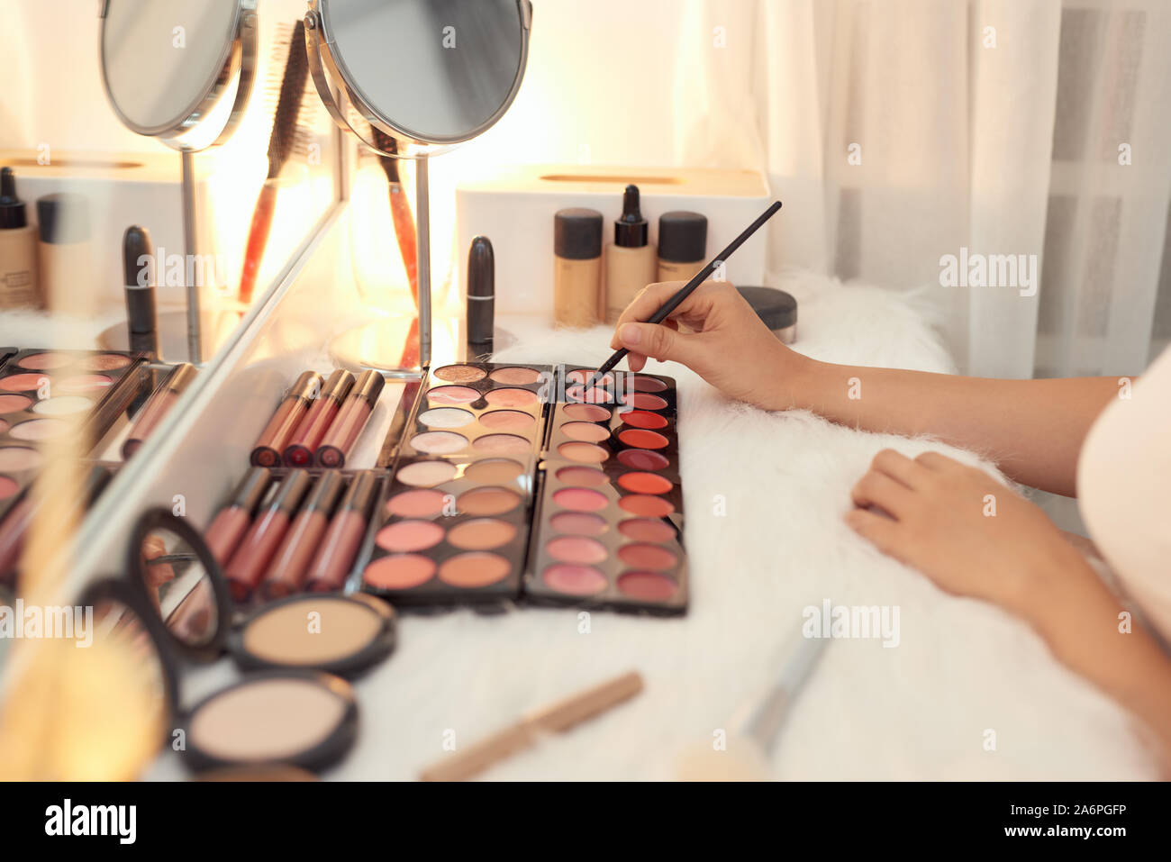 Dekorative Kosmetik und Tools auf Schminktisch in der Nähe von Make-up-Spiegel im Zimmer Stockfoto