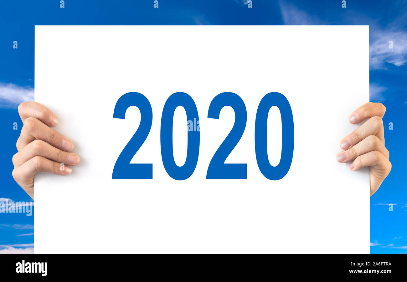 Hände halten eine weiße Tafel mit 2020, blauer Himmel Hintergrund Stockfoto