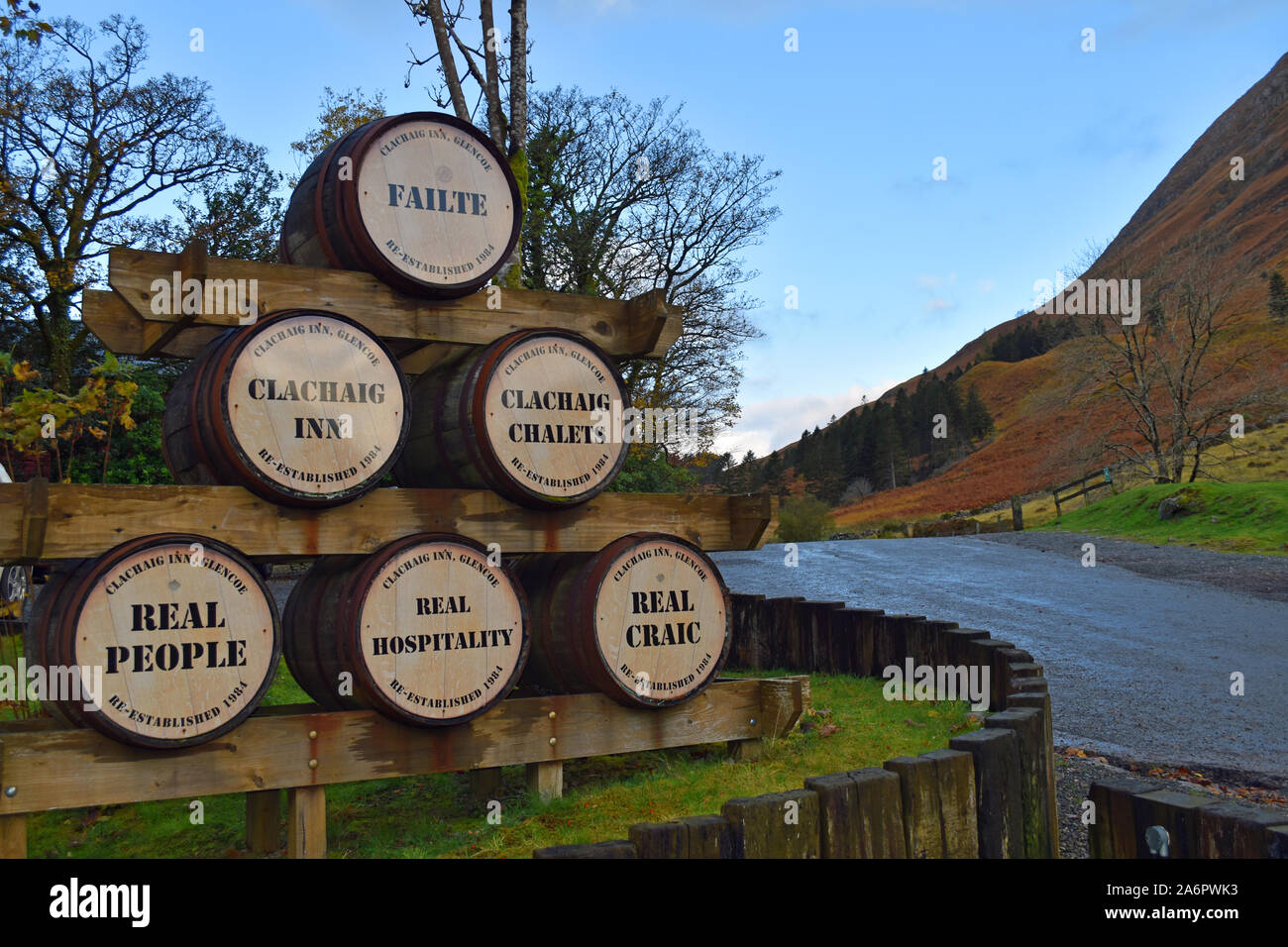 Editorial von Clachaig Inn, Glencoe, Scottish Highlands, Werbung auf bierfässer an der Front des Inn. Berg- und Straße im Hintergrund. Stockfoto