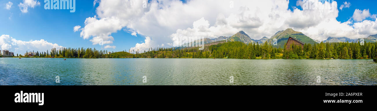 Riesiges Panorama des Berges strba See mit hohen Tatra im Hintergrund. Es gibt eine Sprungschanze, Schwimmen Enten in der Nähe der See Küste Stockfoto