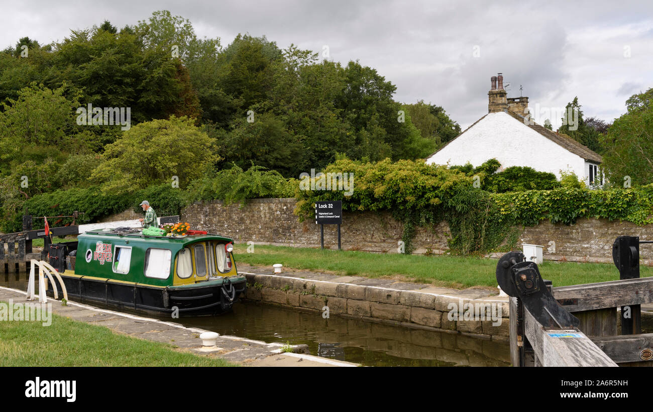 15-04 (schmale Boot) segeln am malerischen ländlichen Leeds Liverpool Canal, vorbei an Schloss (1 Mann durch Tore) - Gargrave, North Yorkshire, England, Großbritannien Stockfoto