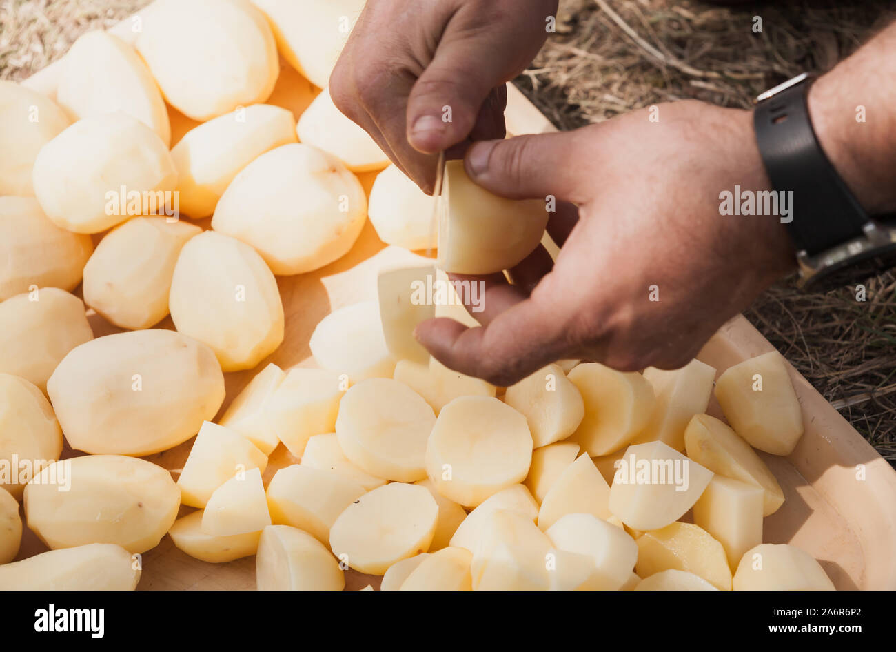 Man schneiden rohe Kartoffeln in Stücke. Kochen Hände mit Messer, Nahaufnahme mit selektiven Fokus Stockfoto