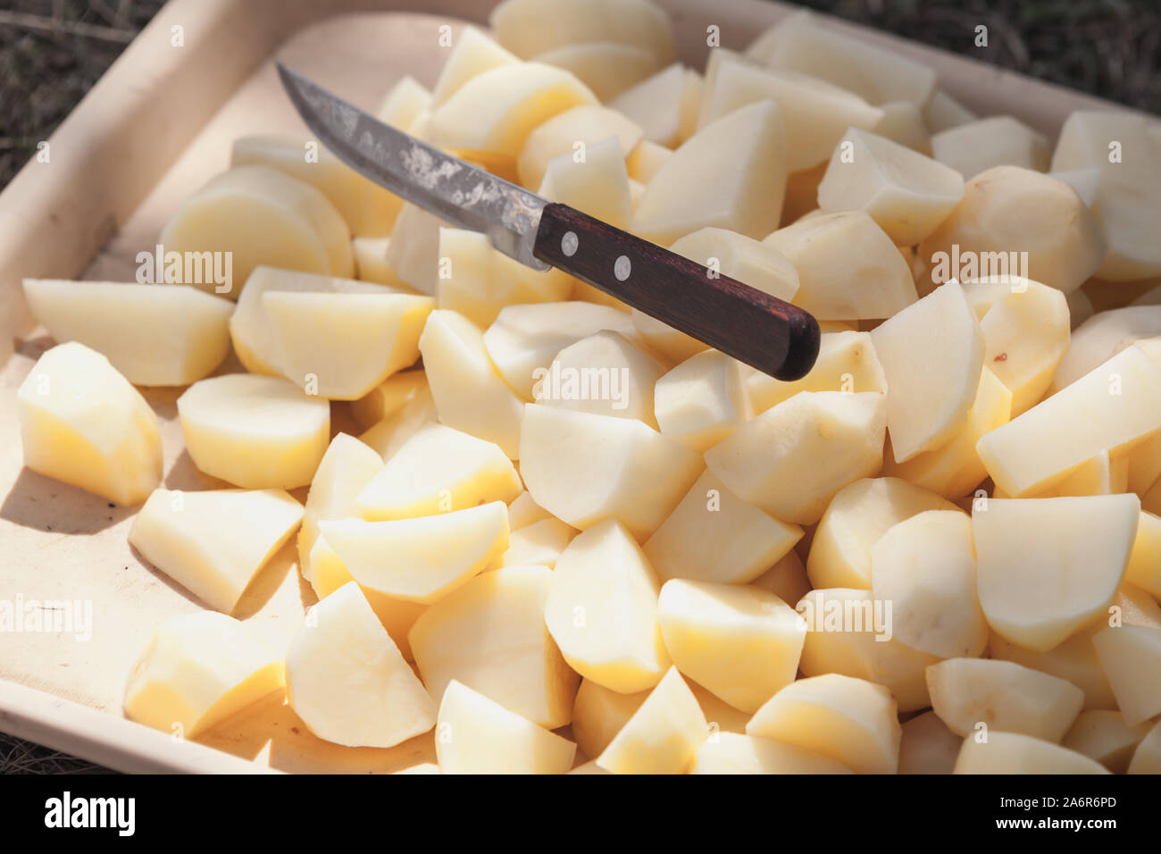 Rohe Kartoffeln in Scheiben und Messer auf einem Tablett legen Stockfoto