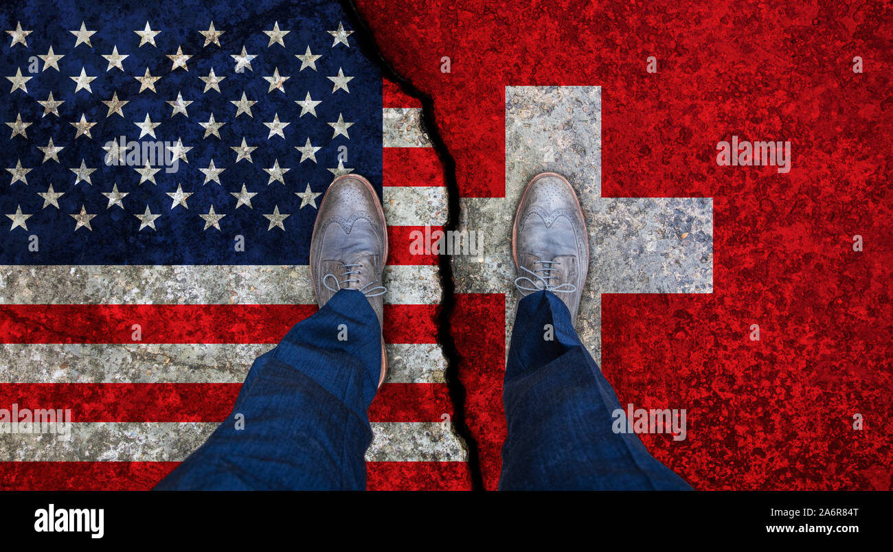 Der Mann steht auf Risse Flaggen der USA und der Schweiz. Politisches Konzept Stockfoto