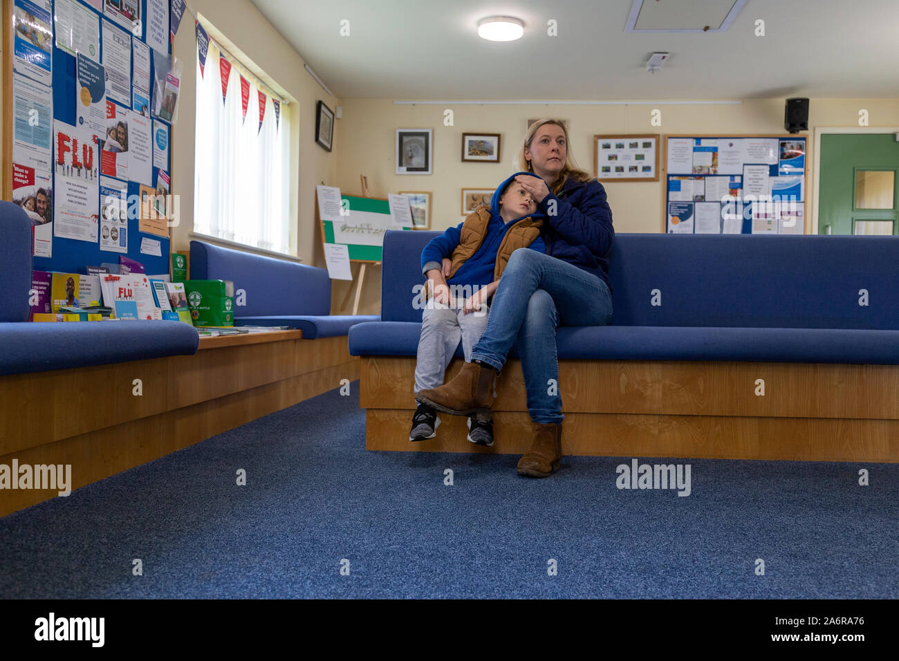 Mutter und Sohn bei General Practitioner, NHS NHS Wartezimmer, Jahre, Erwachsene, Baby - Mensch Alter, Baby Mädchen, Kardiologe, Pflege, Stockfoto