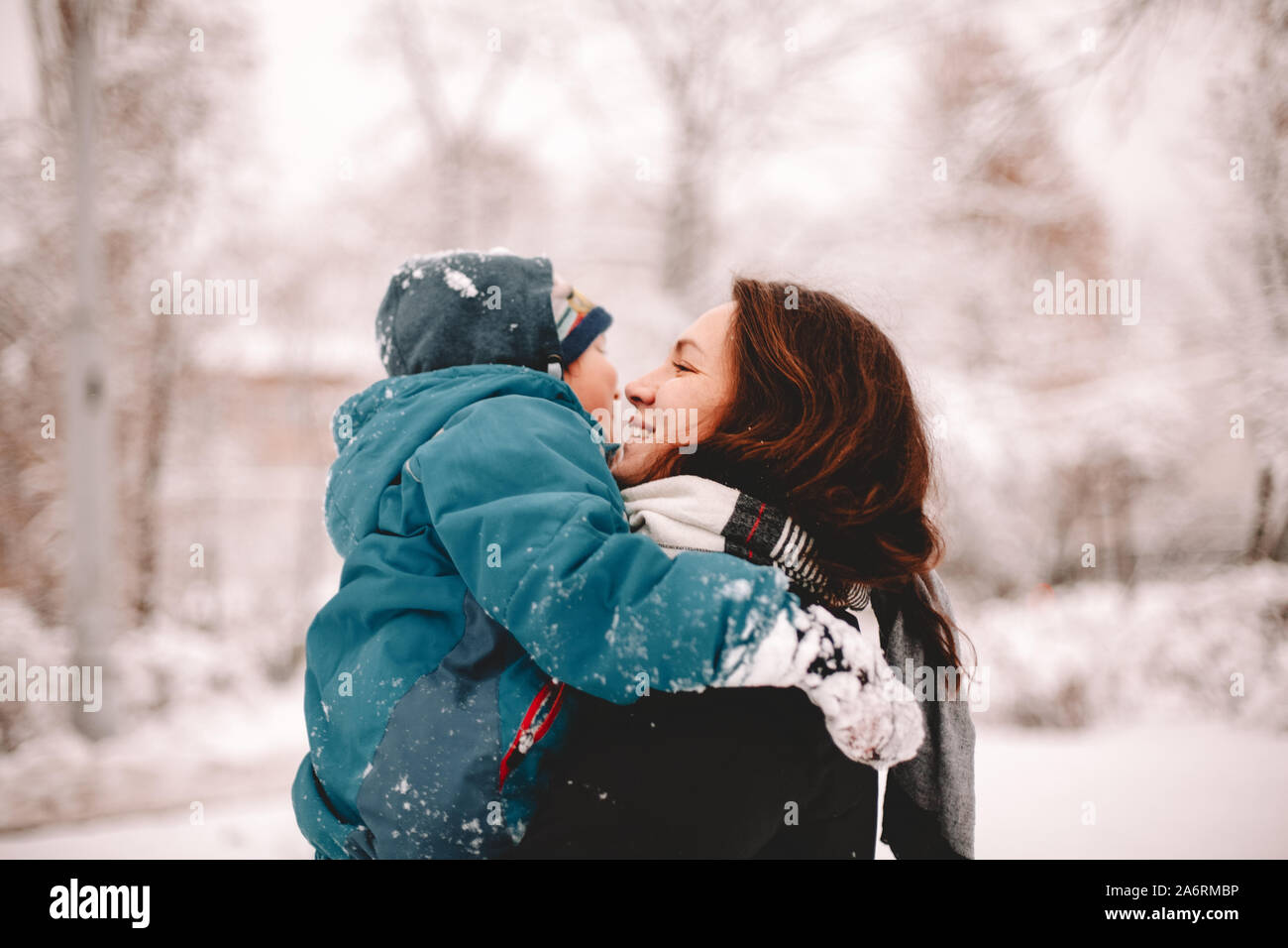 Happy Mother holding Sohn beim Stehen in der Park im Winter Stockfoto