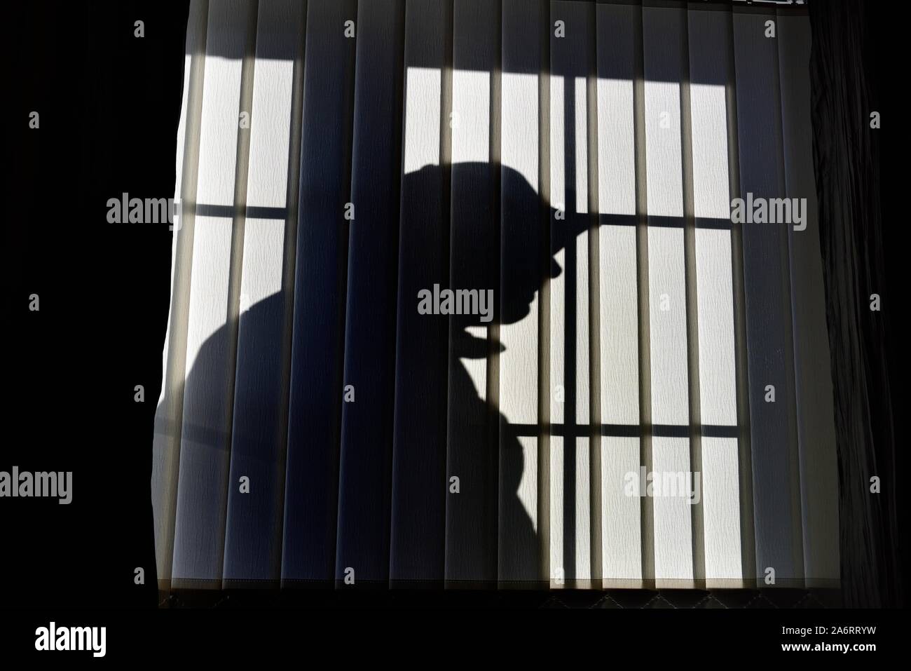 Silhouette männlichen Eindringling, außen ein Fenster mit vertikalen Jalousien Stockfoto