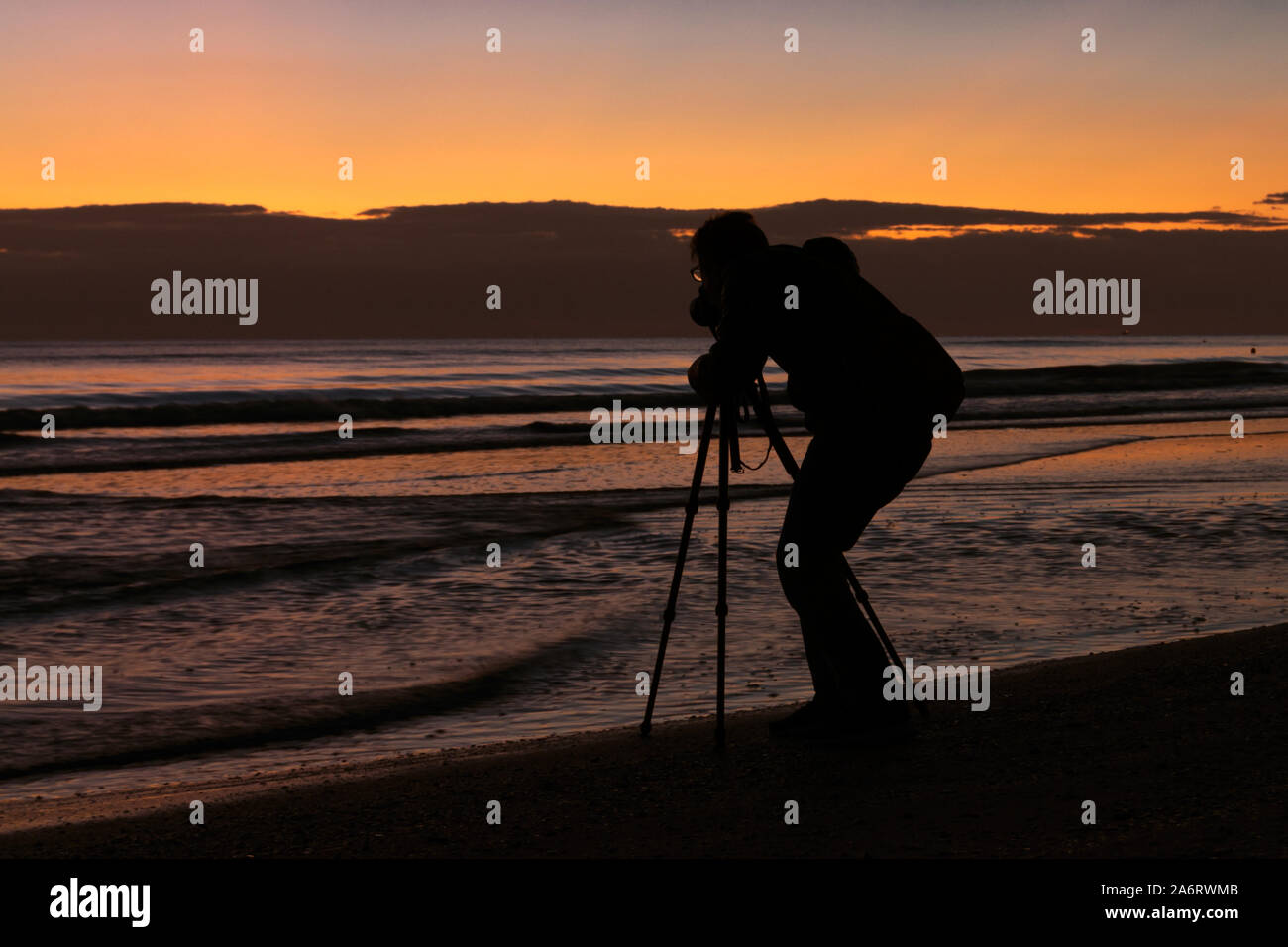 Silhoutte von professionellen Fotografen Fotos mit einer Kamera und einem Stativ in der Strand bei Sonnenaufgang. Schönen Sonnenaufgang auf dem Hintergrund Stockfoto