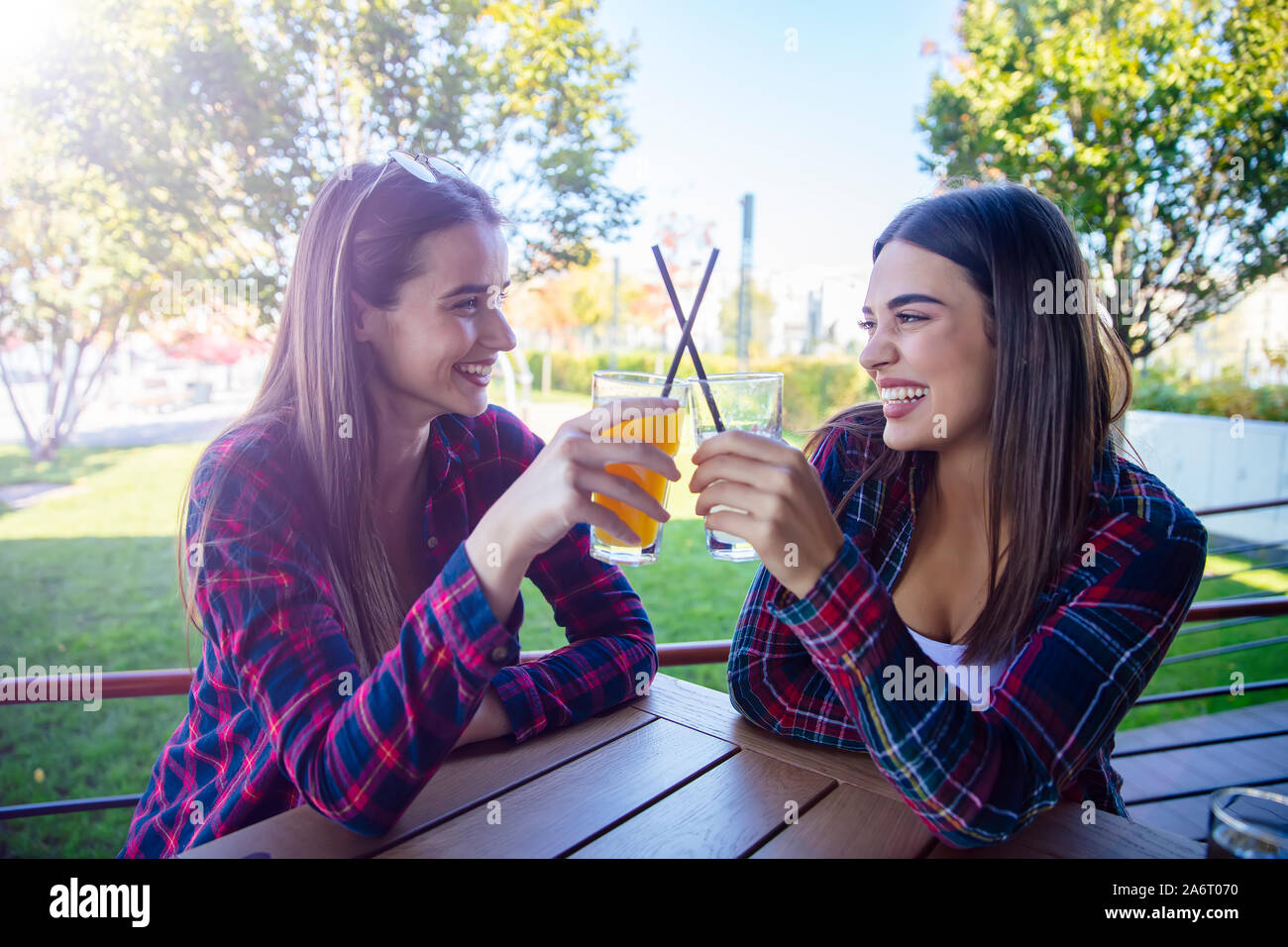 Zwei junge Frauen trinken Saft und Limonade in den Park an einem sonnigen Tag Stockfoto