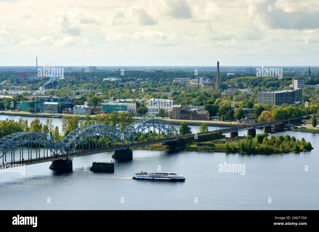 Ein Ausflugsboot durch die Eisenbahnbrücke, in den Fluss Daugava. Riga, Lettland Stockfoto
