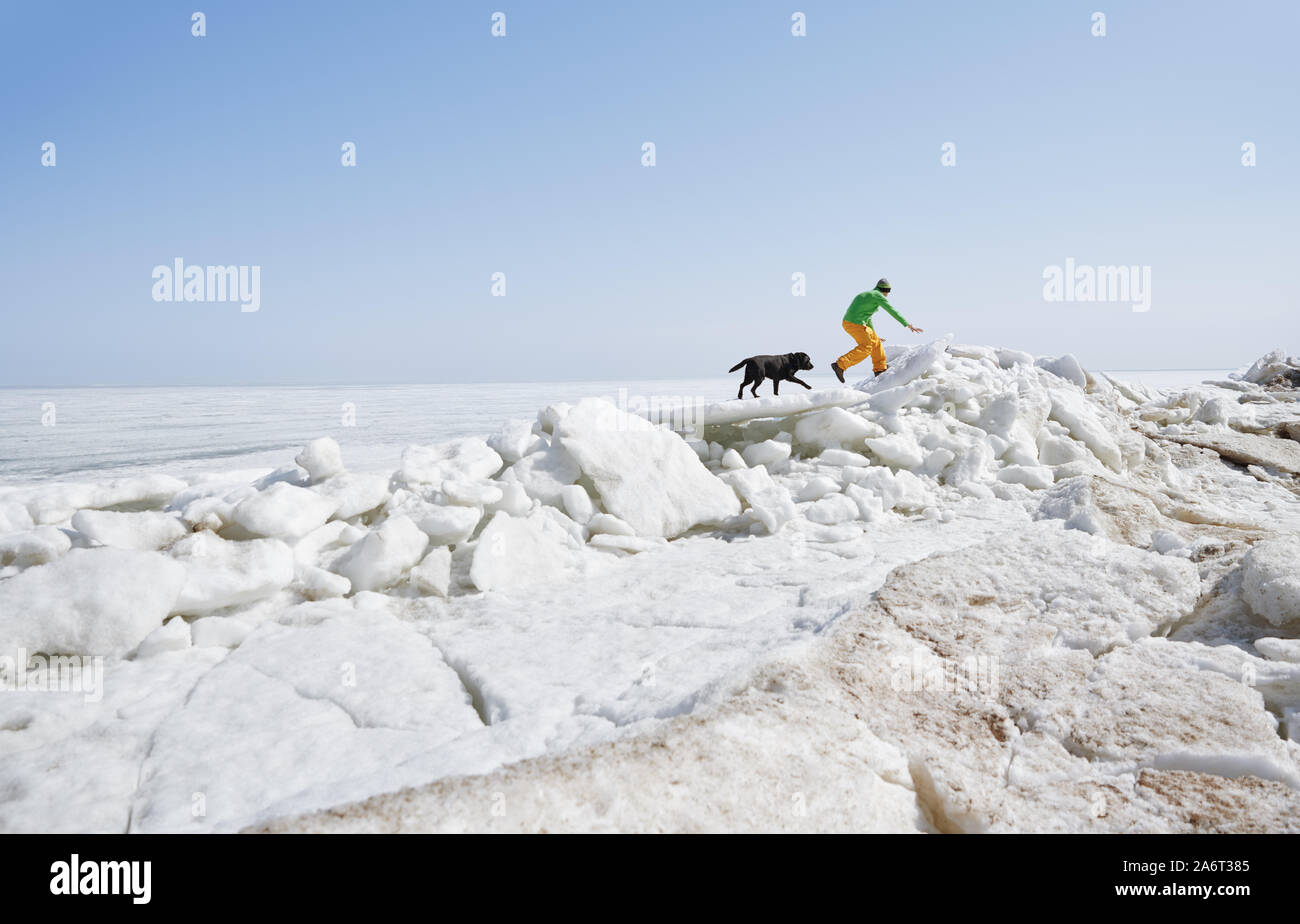 Junge erwachsene Mann draußen mit seinem Hund Spaß im Winter Landschaft Stockfoto