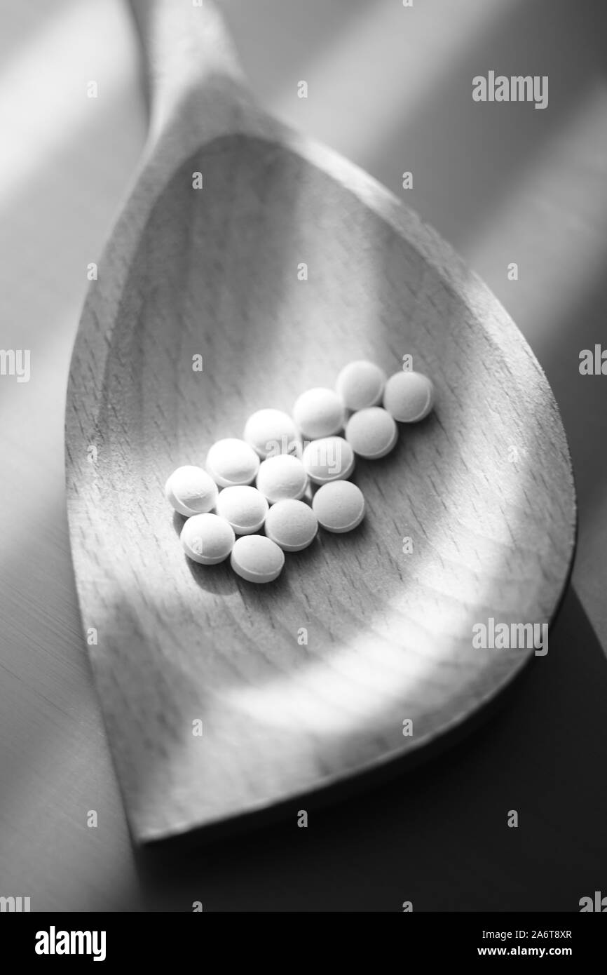 Medizinische Pillen in einem Löffel aus Holz. Schwarze und weiße poto. Stockfoto