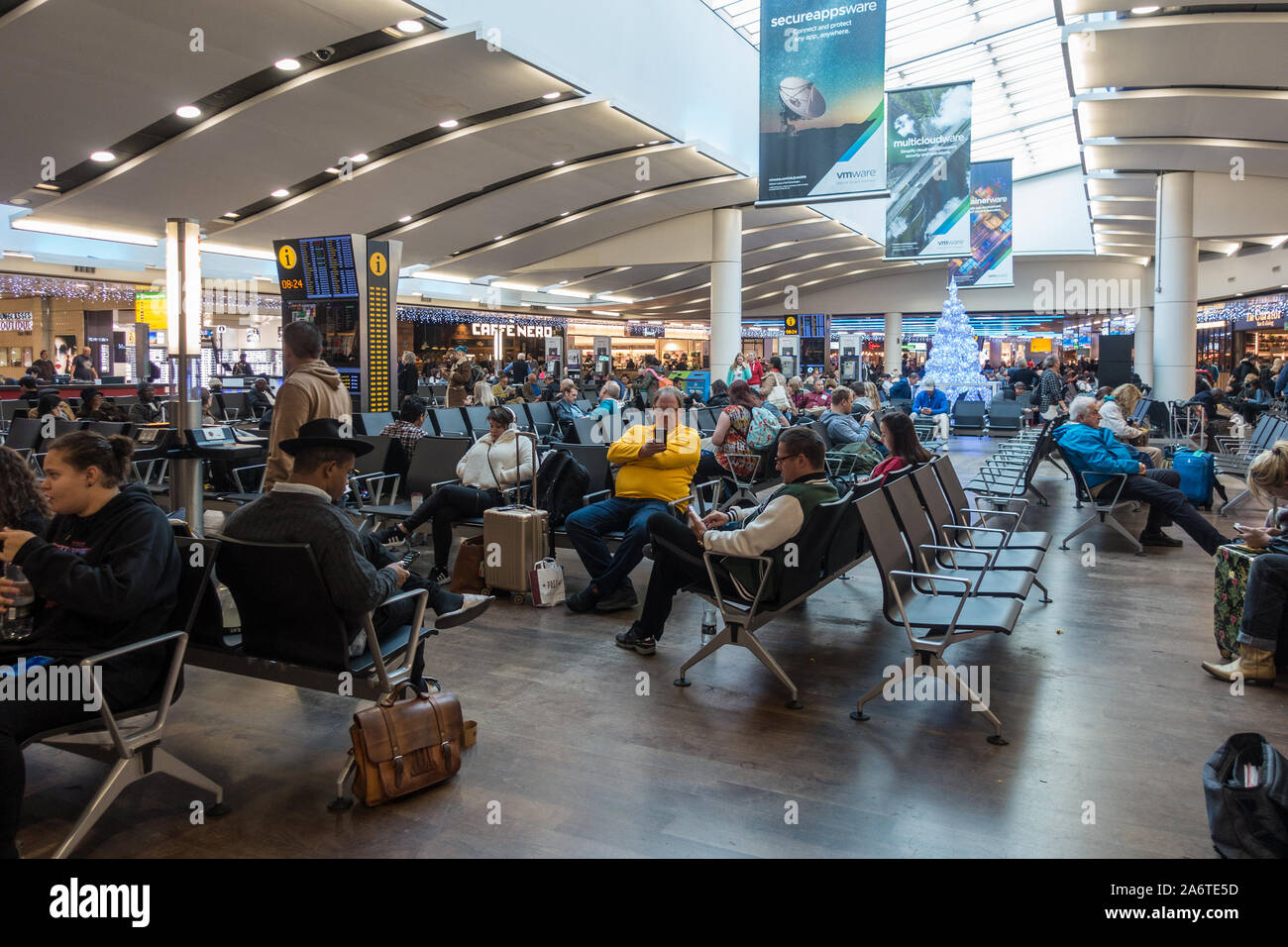 Die Leute sitzen und für ihre Flüge in die Abflughalle am Flughafen Heathrow Terminal 3 warten. Stockfoto