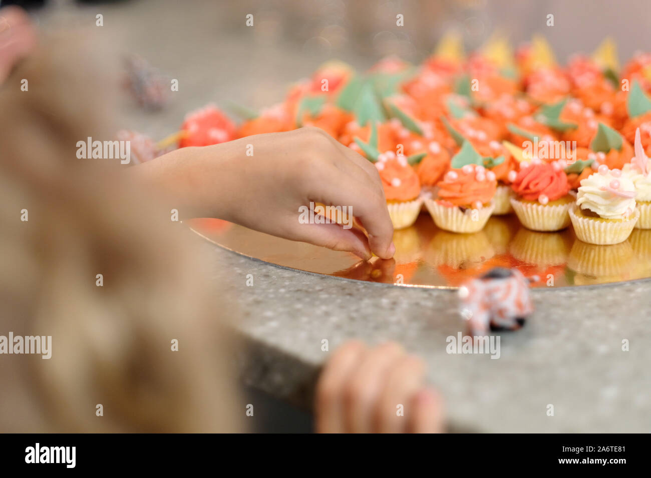 Das Kind wählt eine bunte Miniatur Kuchen in der Partei Stockfoto