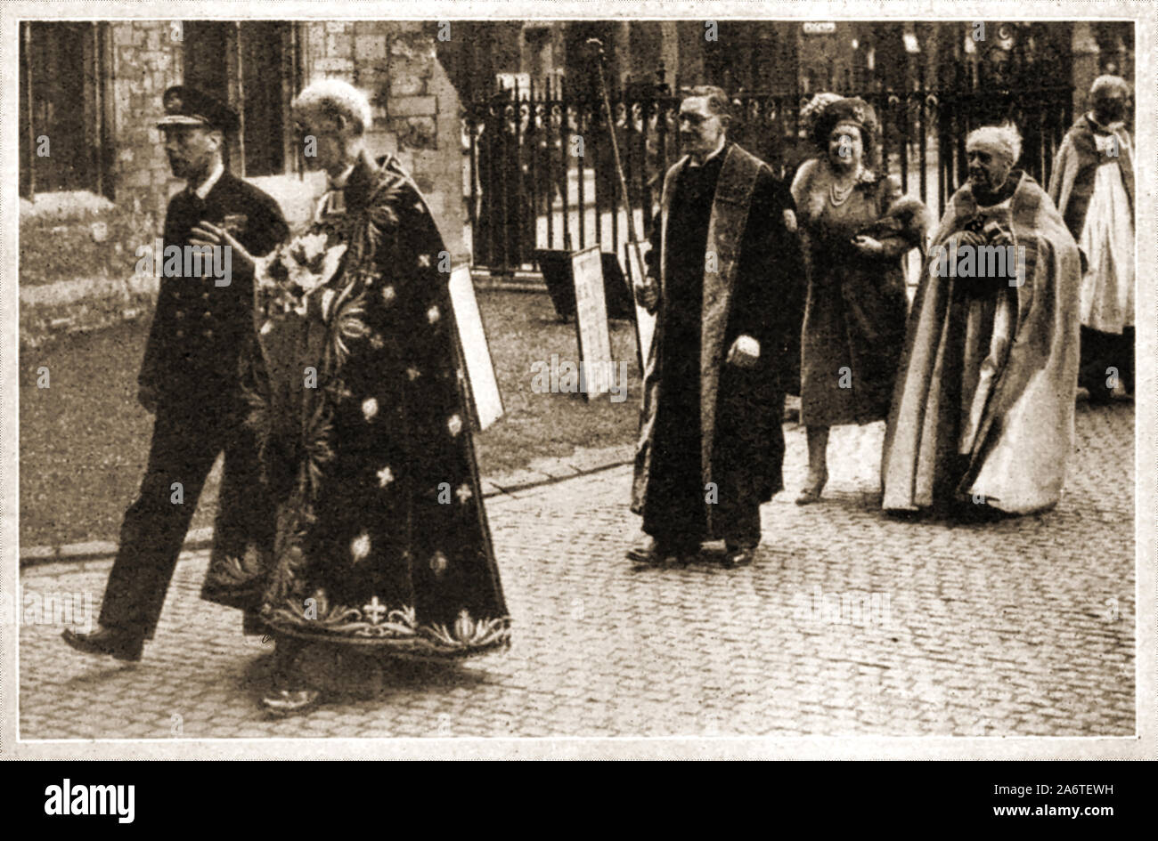 MAUNDAY/MAUNDY MONEY ca. 1940 - König George VI. von England verbindet hochrangige Geistliche und Queen Elizabeth seine Frau (hinter Fuß) für die der jährlichen Zeremonie der Verteilung von maundy Geld nach der ein Gottesdienst in der Kirche von England am Gründonnerstag, dem Tag vor Karfreitag, wenn der britische Monarch Zeremoniell verteilt kleine silberne Münzen als 'Maundy Geld" bekannt als symbolischer Almosen Stockfoto