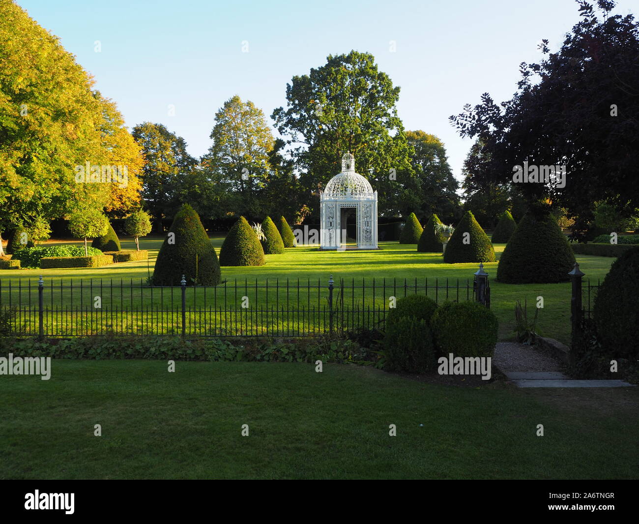 Das Parterre an chenies Manor Garden, Buckinghamshire. Der weiße Vogel käfig Pagode ist in zwischen den Reihen der formgehölze in der Abendsonne. Stockfoto