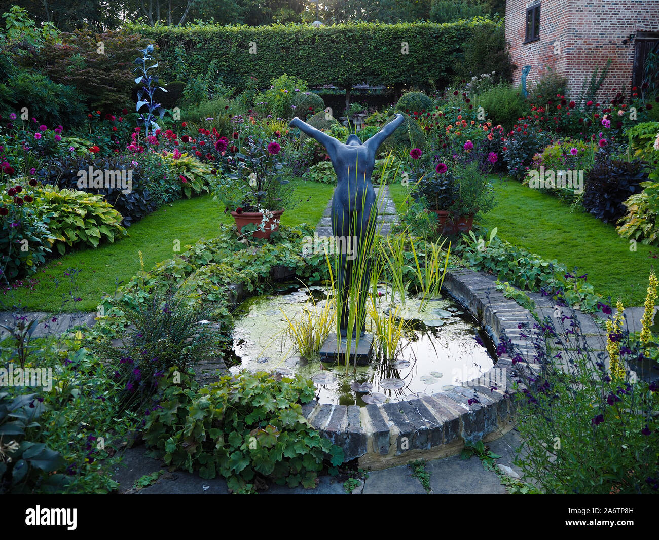 Niedrige Sommer Abend Sonne, ein Pool von Licht auf chenies Manor Sunken Garden Zierteich; empfohlene Skulptur bis durch die Dahlien. Stockfoto
