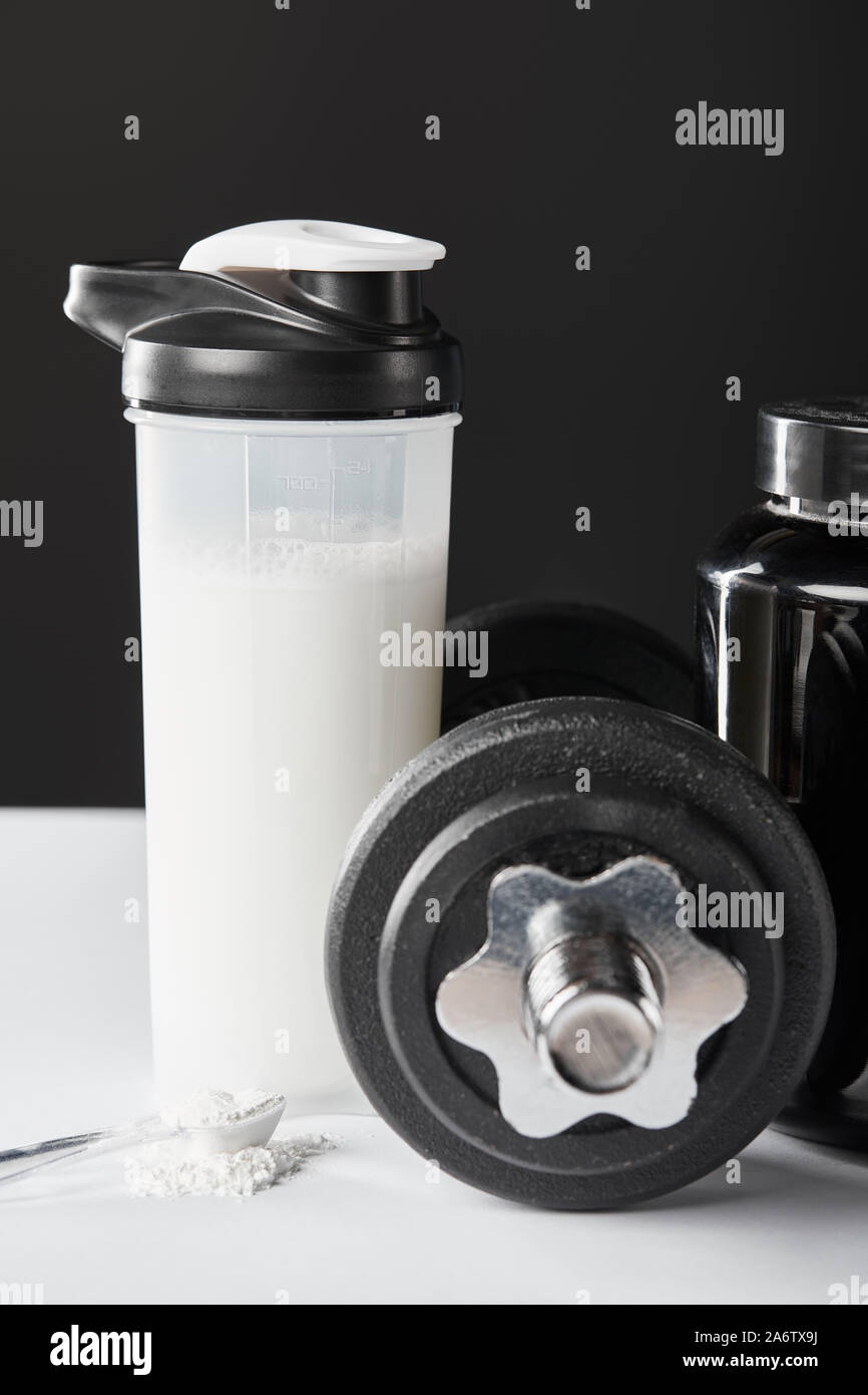Löffel mit Protein in der Nähe von hantel und Sport Flasche mit Protein  Shake auf Schwarz Stockfotografie - Alamy