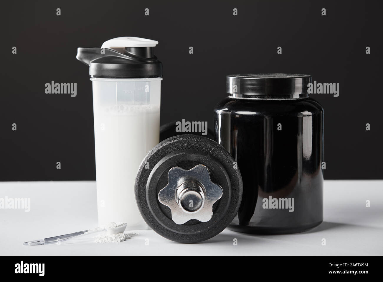 Löffel in der Nähe von hantel und Sport Flasche mit Protein Shake auf  Schwarz Stockfotografie - Alamy