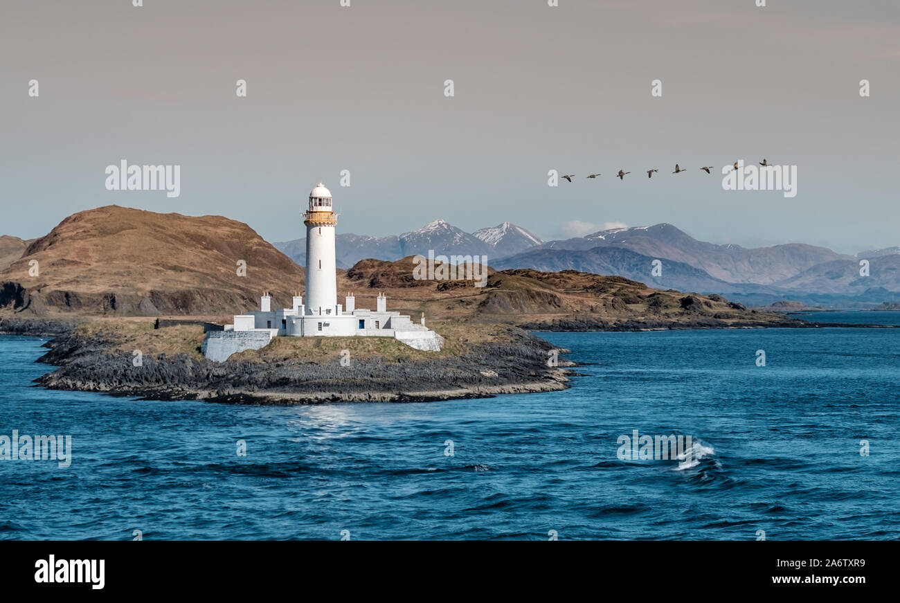 Der alte Leuchtturm in Schottland Highland, mit schneebedeckten Gipfeln im Hintergrund Stockfoto