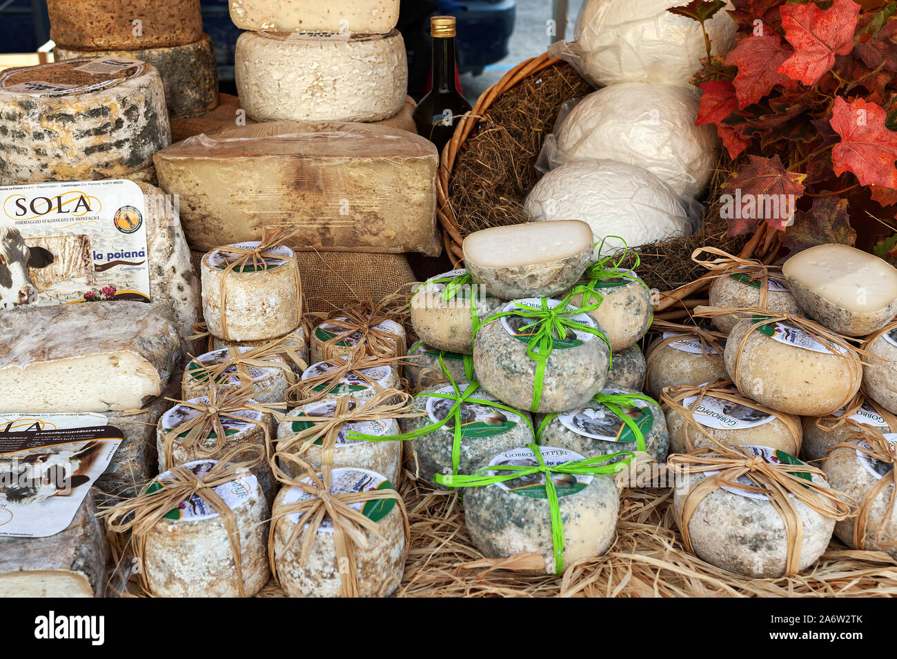 Kleine harte Handwerkerkäses im Stroh auf dem Bauernmarkt gewickelt. Stockfoto