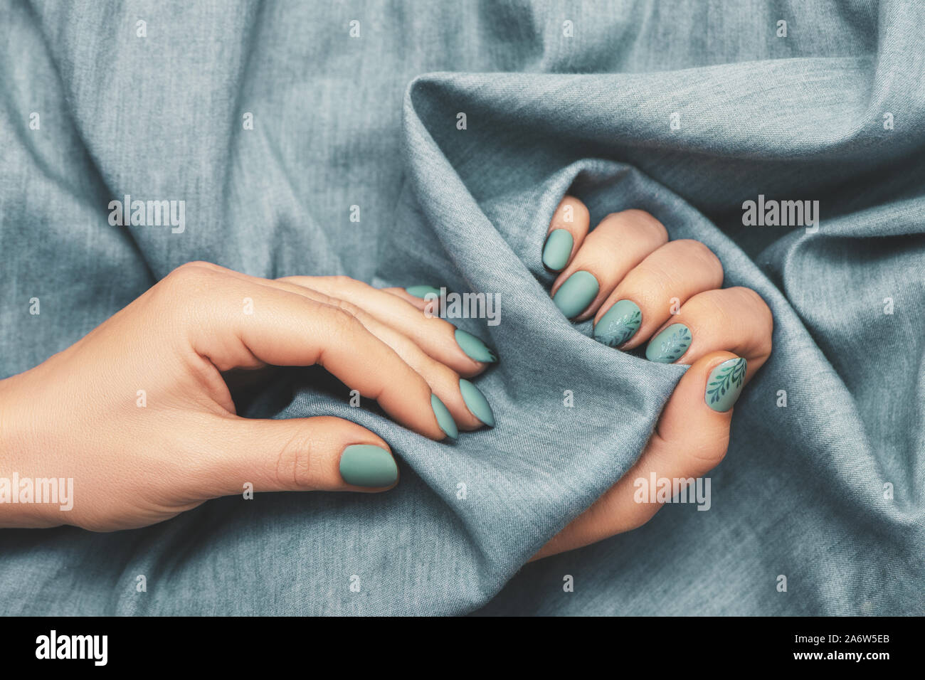 Nahaufnahme von Frau Hände mit trendigen Maniküre auf Jeans Hintergrund Tuch. Ansicht von oben. Stockfoto