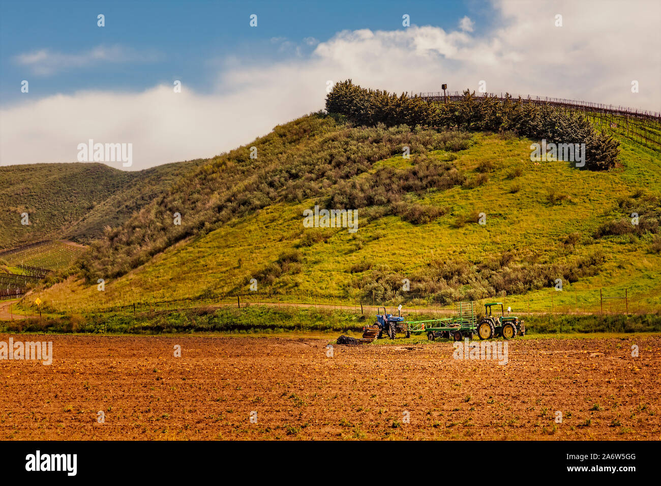 California Wine Yards - Blick auf eine John Deere Traktor und blau Landmaschinen neben der Weinberge an der Pazifikküste von CA. Stockfoto